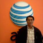 A person stands in front of an orange wall with a large AT&T logo.